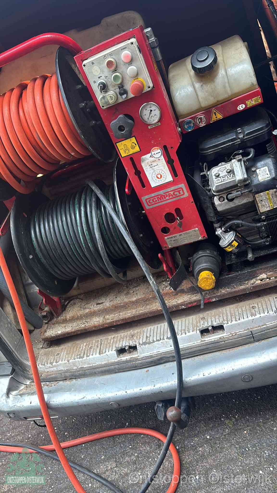 Een rood hogedruk-rioolreinigingstoestel in de laadbak van de bedrijfsbus, apparatuur voor een hardnekkige afvoerverstopping in Oisterwijk