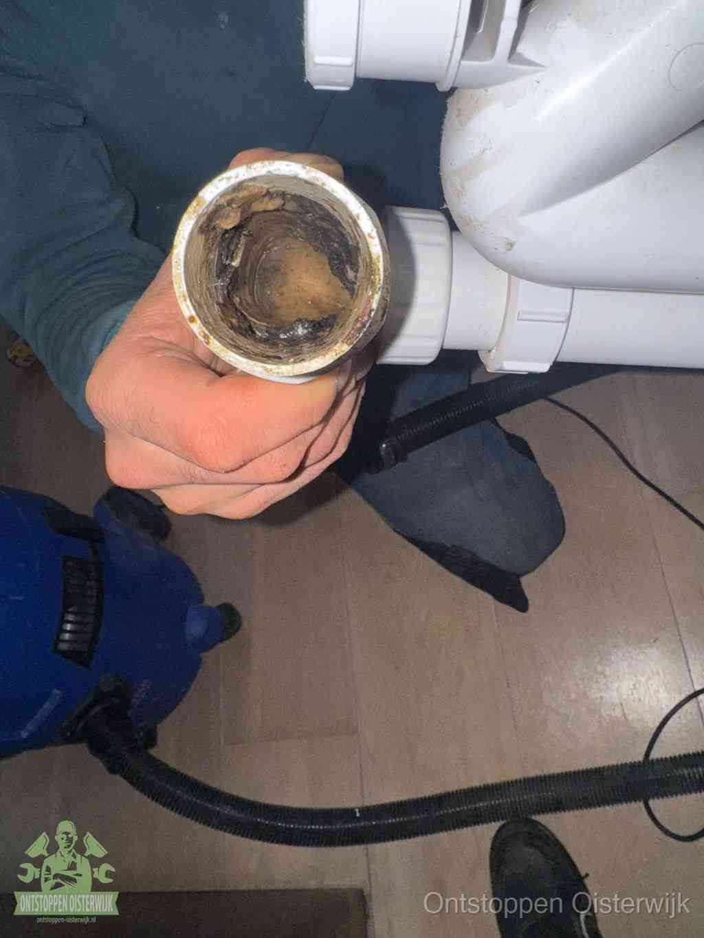 Een losgekoppelde afvoerbuis die van binnen volledig is dichtgeslibd met vet en aanslag, de meest voorkomende oorzaak van een verstopte gootsteen in Oisterwijk
