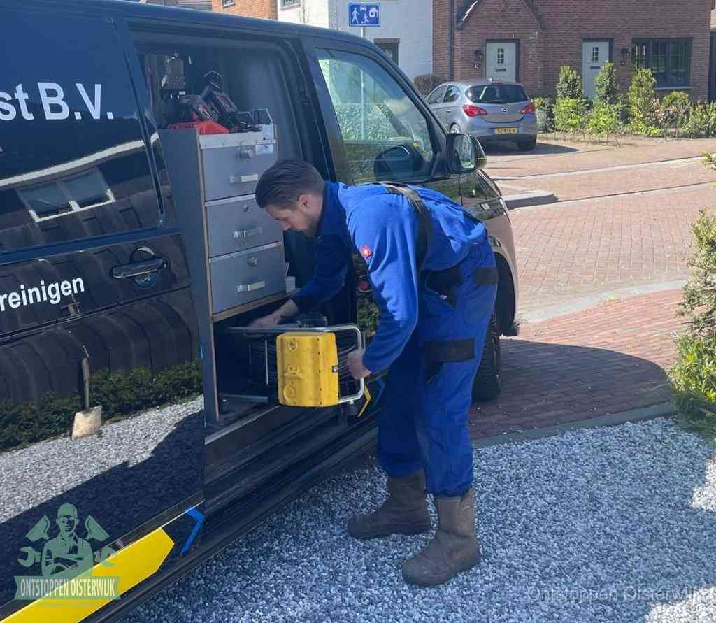 Een monteur pakt buiten op de oprit gereedschap uit de bedrijfsbus, het moment om een professional in te schakelen voor een verstopte afvoer in Oisterwijk