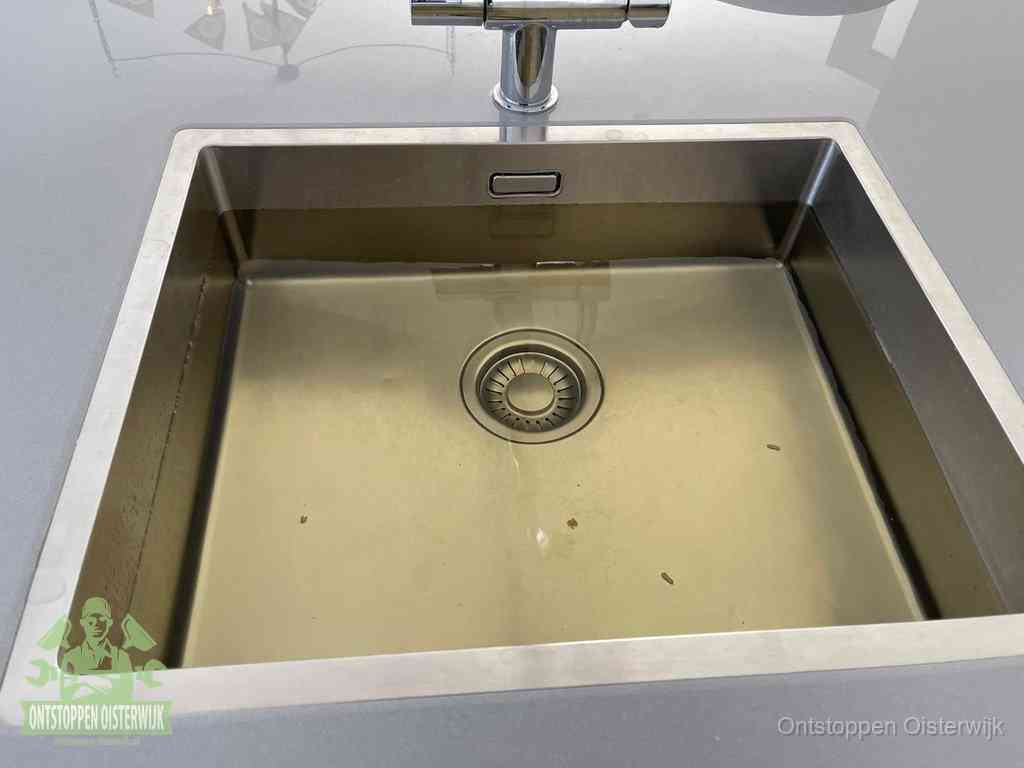 Stilstaand water in een rvs spoelbak dat niet wegloopt, een duidelijk signaal van een gootsteenverstopping in Oisterwijk