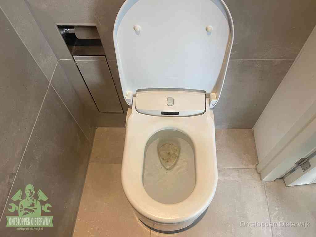 Een wit hangtoilet waarin een prop wc-papier op het water blijft drijven, een duidelijk signaal van een verstopte wc in Oisterwijk