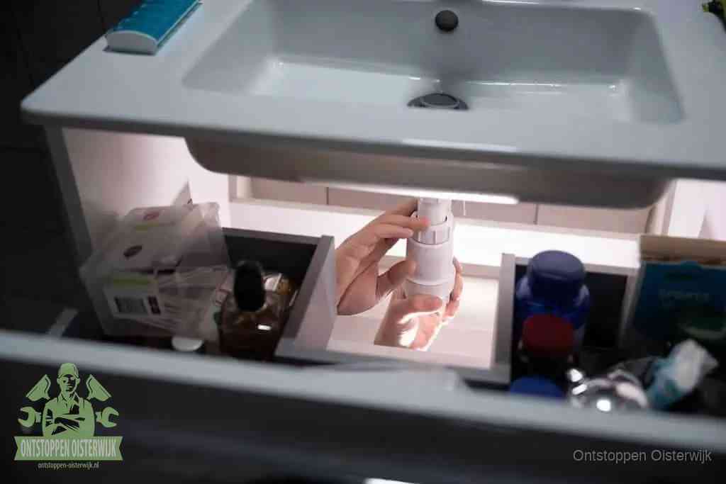 Een pompfles met zeep boven een wastafel in de toiletruimte, de warm water en afwasmiddel-methode om de wc te ontstoppen in Oisterwijk