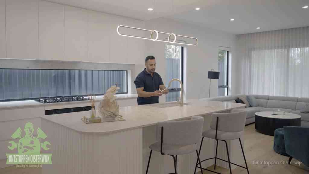 Een bewoner bij de keukenspoelbak die zelf aan de slag gaat met een verstopte gootsteen in Oisterwijk