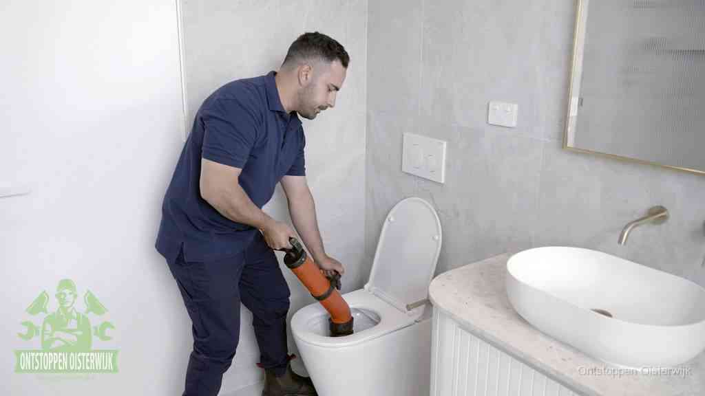 Een man gebruikt een handmatige luchtdruk-ontstopper in een modern betegeld toilet om zelf de wc te ontstoppen in Oisterwijk